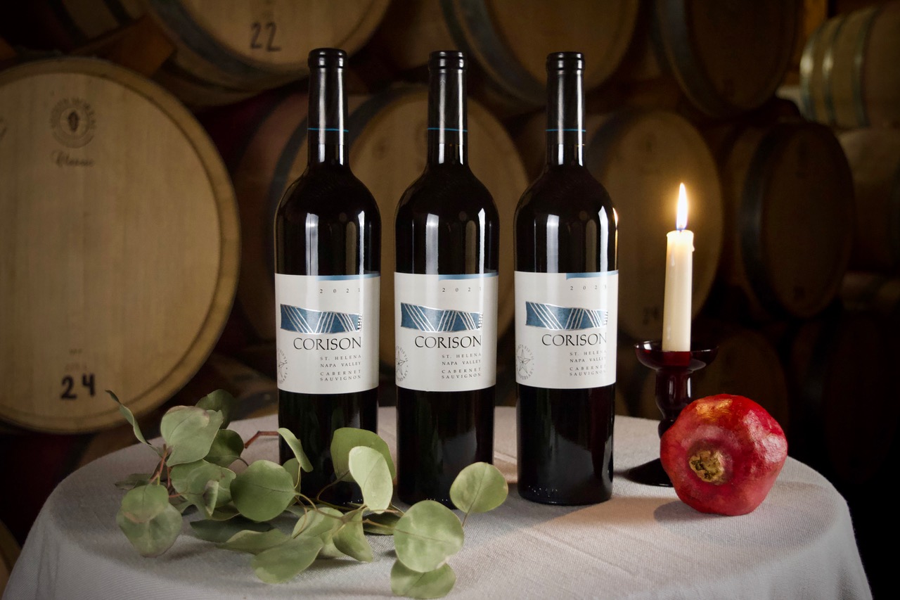 Three bottles of 2021 Corison Napa Valley Cabernet Sauvignon on a festive holiday table in the winery barrel room.