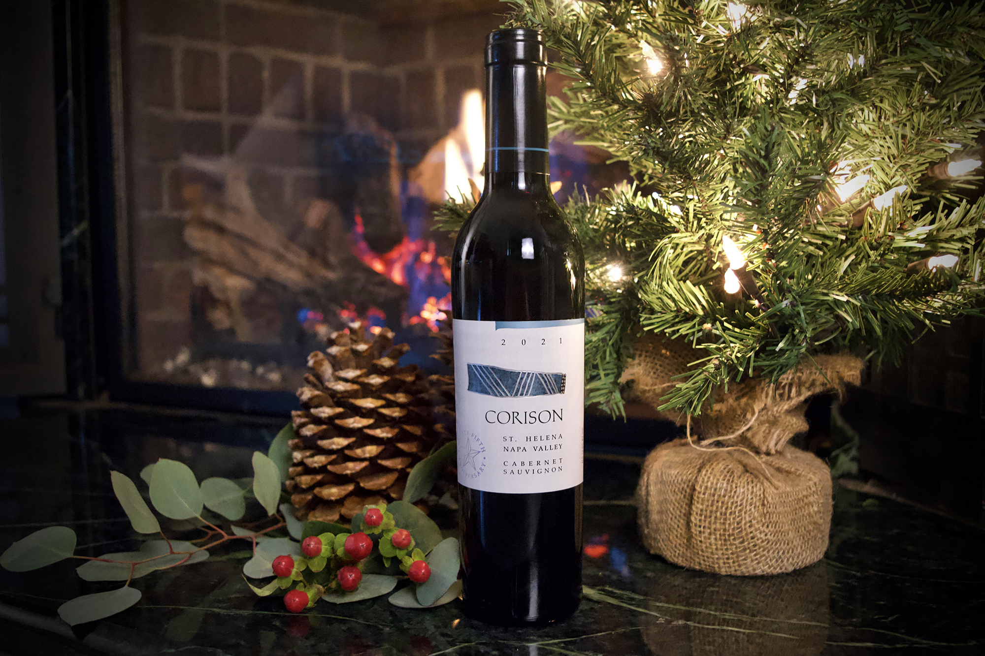 A half-bottle (375ml) of the 2021 Corison Napa Valley Cabernet Sauvignon by a mini Christmas tree in front of a fireplace.